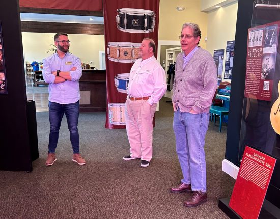 Three men standing at the Gretsch exhibit.
