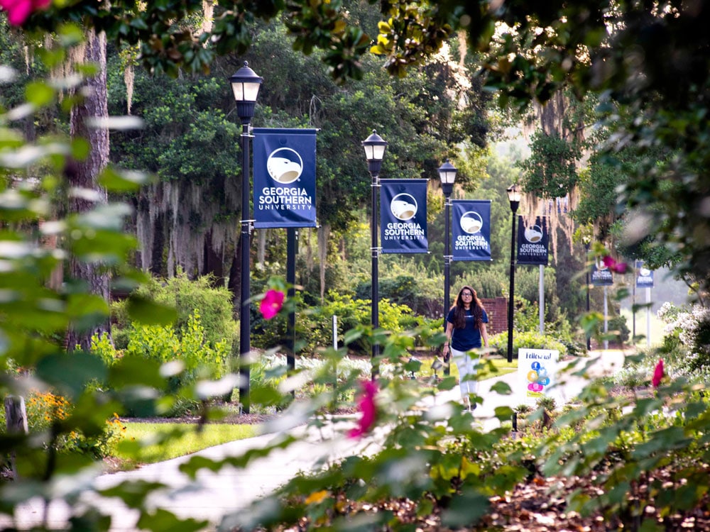 A student walks down a pathway on the Armstrong campus of Georgia Southern University.