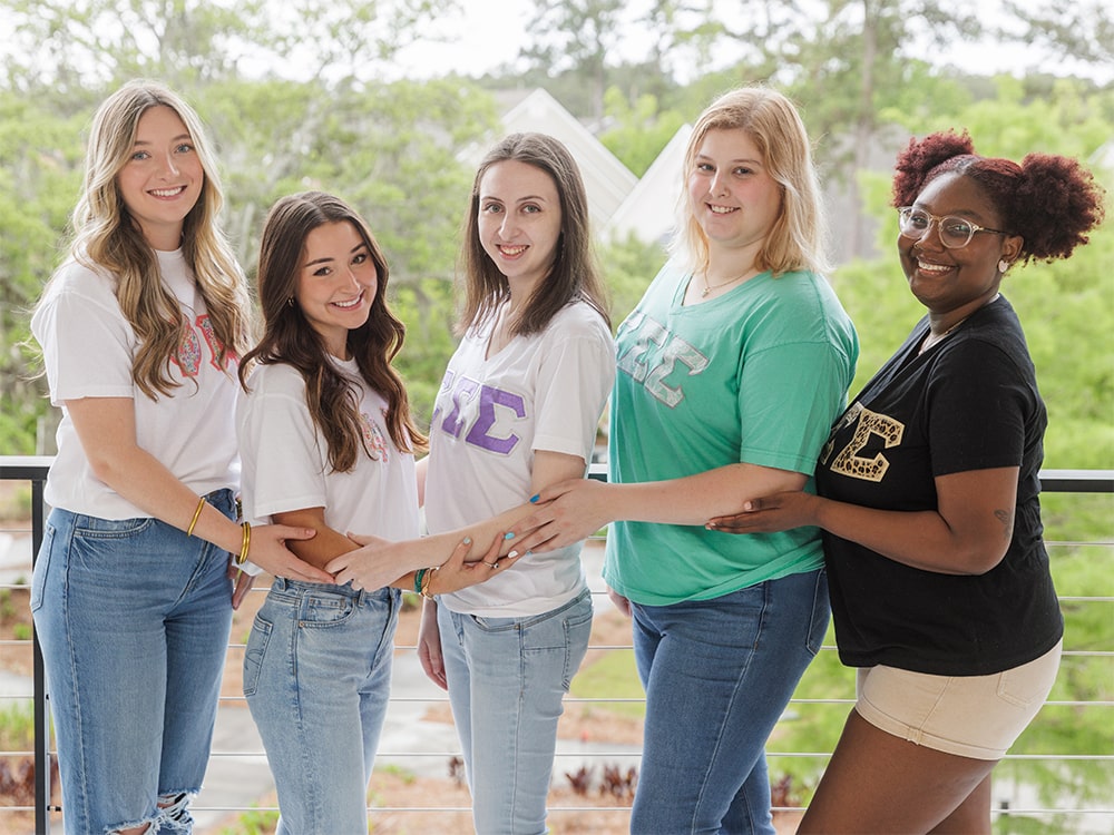 Georgia Southern sorority members smiling and posing together outdoors in matching Greek letter shirts.