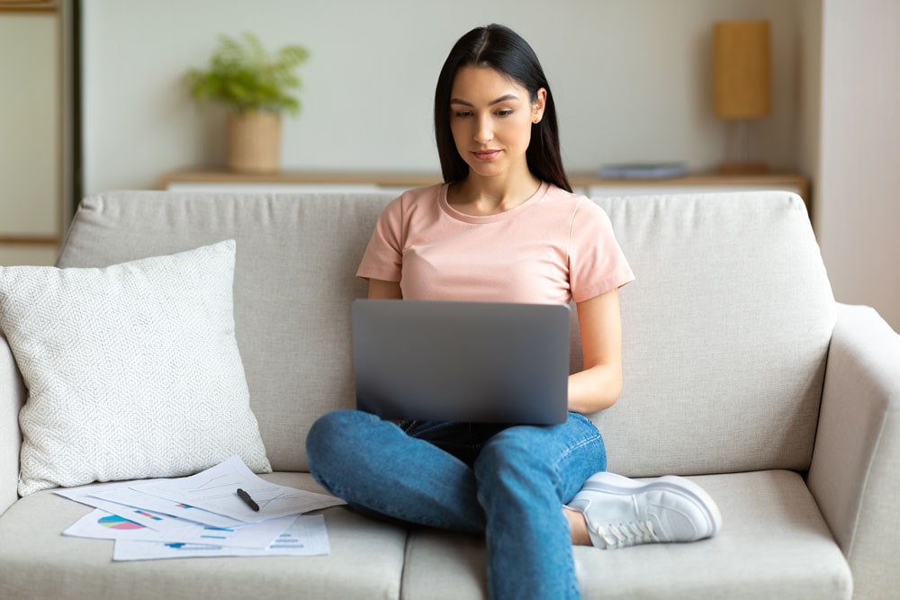 A student on the Georgia Southern campus sits on a couch while studying on her laptop.