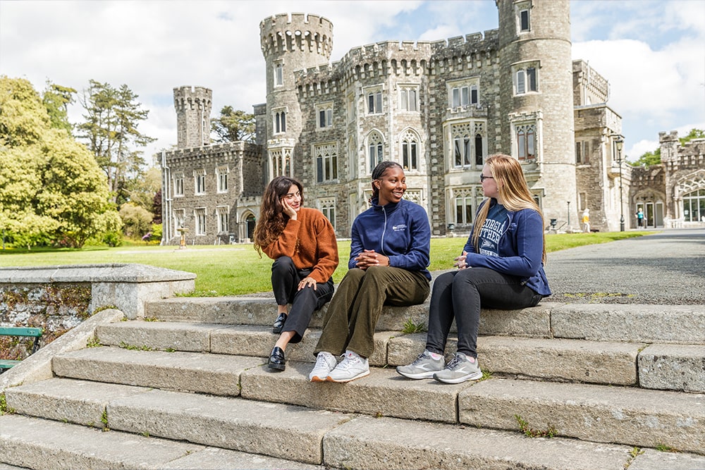 Students seated on steps in front of a castle near Wexford, Ireland.