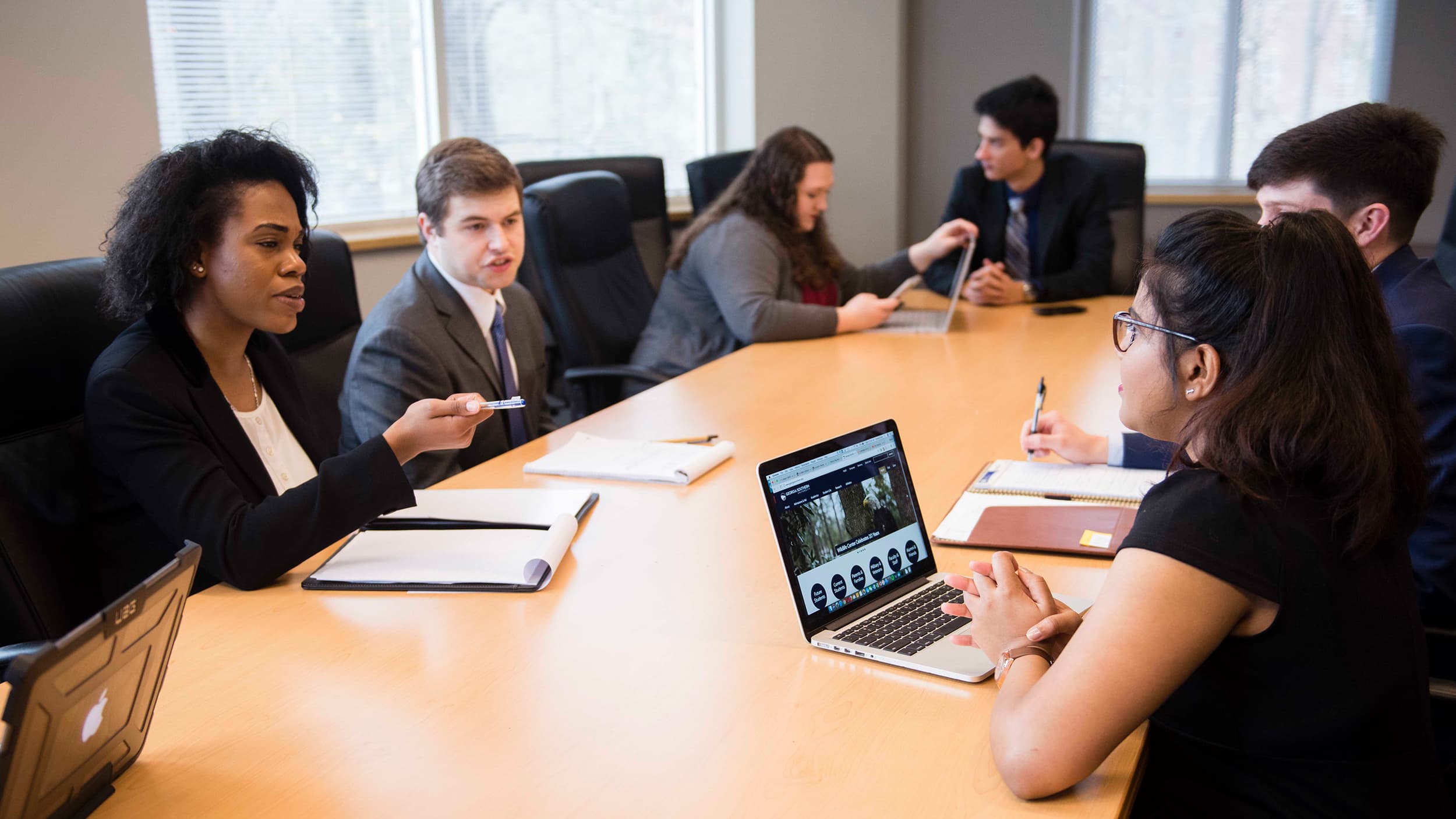A group of young professionals in Georgia Southern School of Accountancy gather in a boardroom.