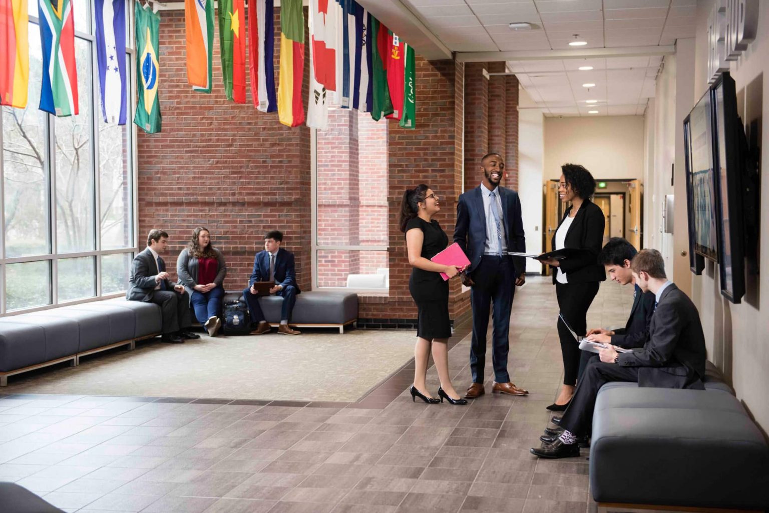 Parker College of Business students networking and studying in a hallway with international flags overhead.