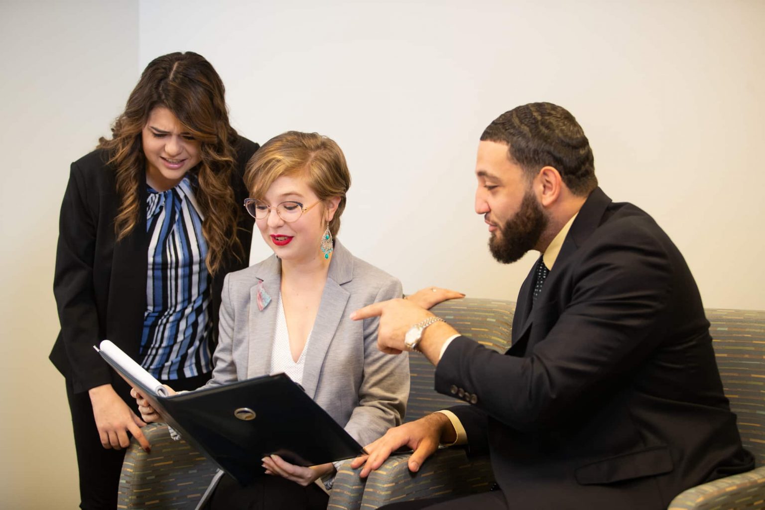 Three staff members from the Parker College of Business reviewing a notebook