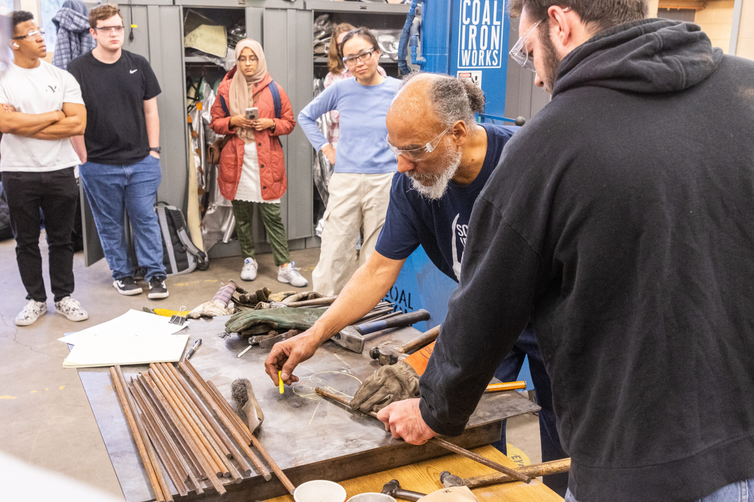 An instructor demonstrates metal-working techniques in the blacksmithing forge lab.