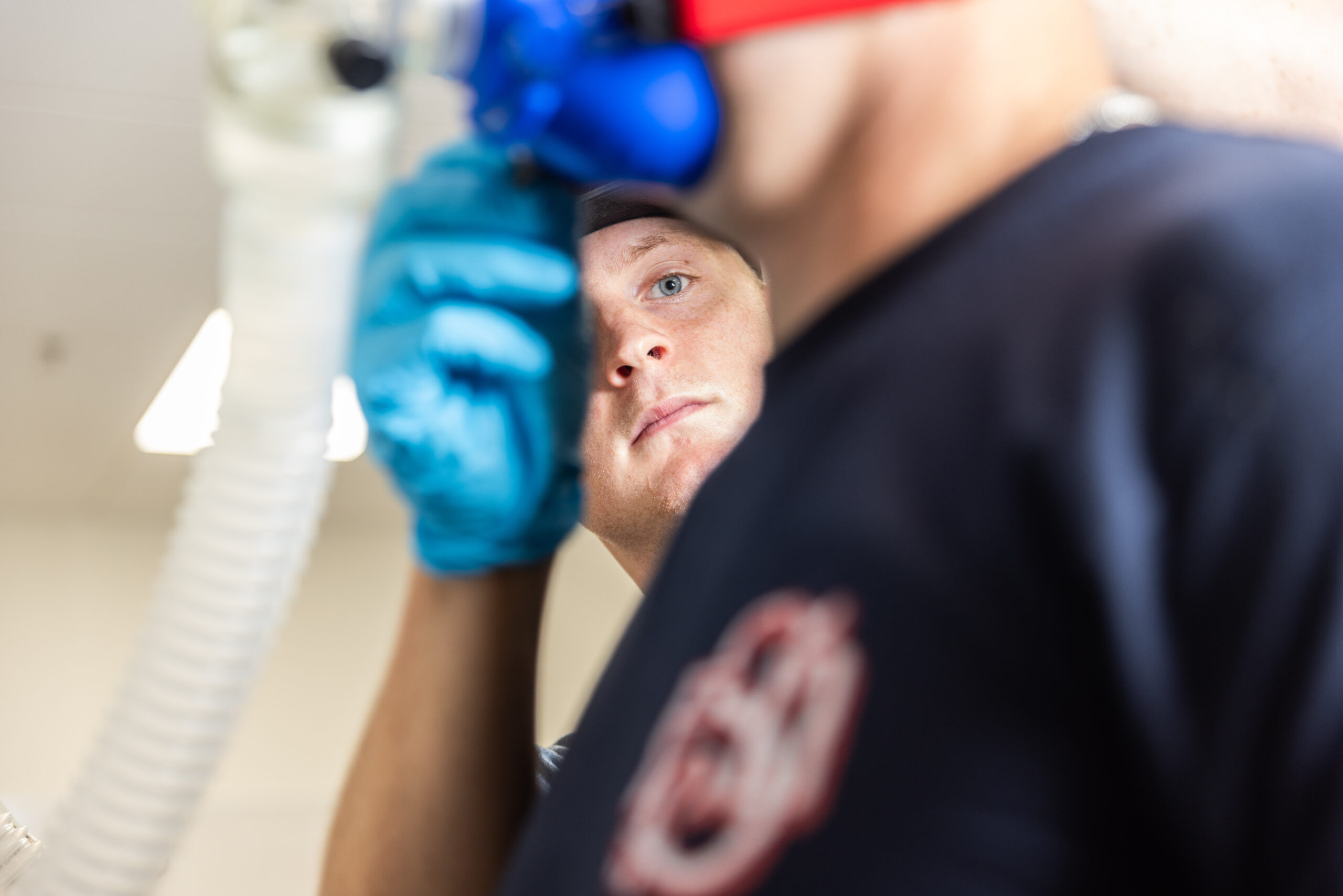 A student adjusts a face mask to study respiratory conditions for holistic fitness studies.