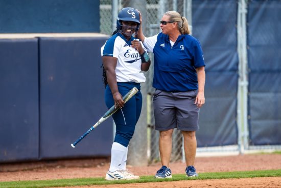 Georgia Southern graduate in kinesiology encourages softball athlete on the field.