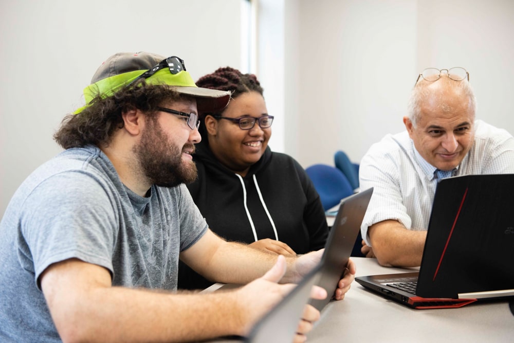Three ethnically diverse individuals learning computer engineering.