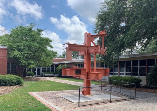 Exterior view of the Carruth Building at Georgia Southern, featuring a large orange steel beam structure in the courtyard.