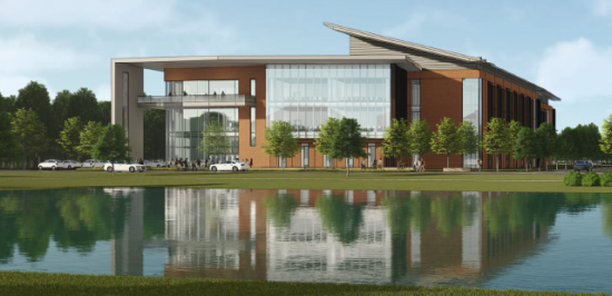 Exterior view of the College of Engineering building reflected in a pond, with trees and cars lining the entrance.