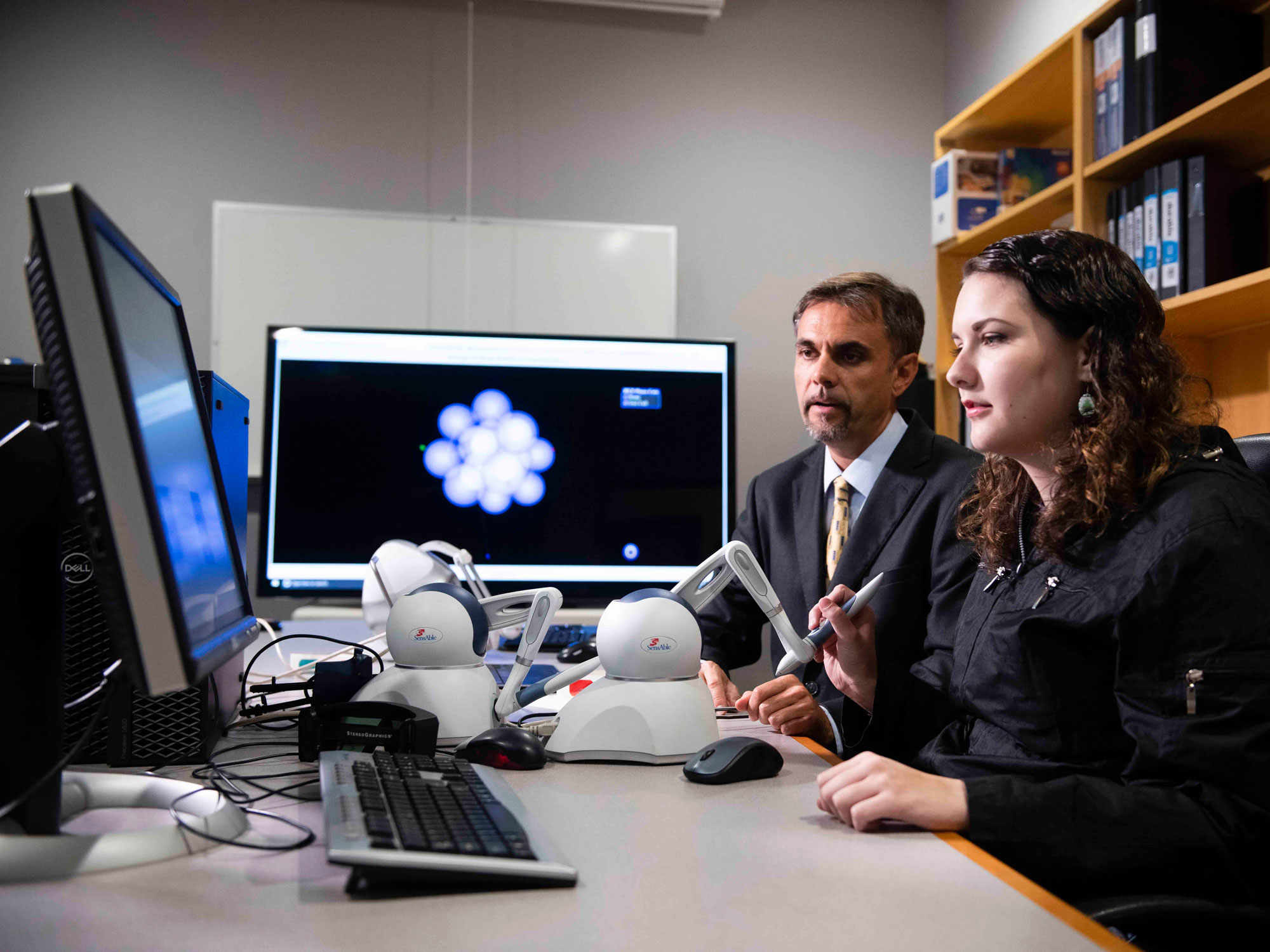 A student and teacher in the Georgia Southern Computer Science, B.S. Program use a computer and some accessory devices to work on a project.