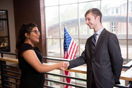 Two Georgia Southern students in business clothes shake hands