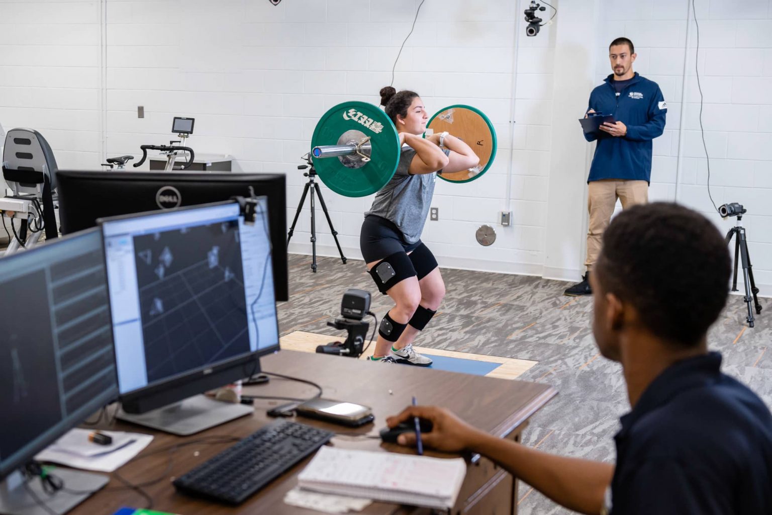 Georgia Southern Students monitor a student athlete performing a power clean during a kinesiology test.
