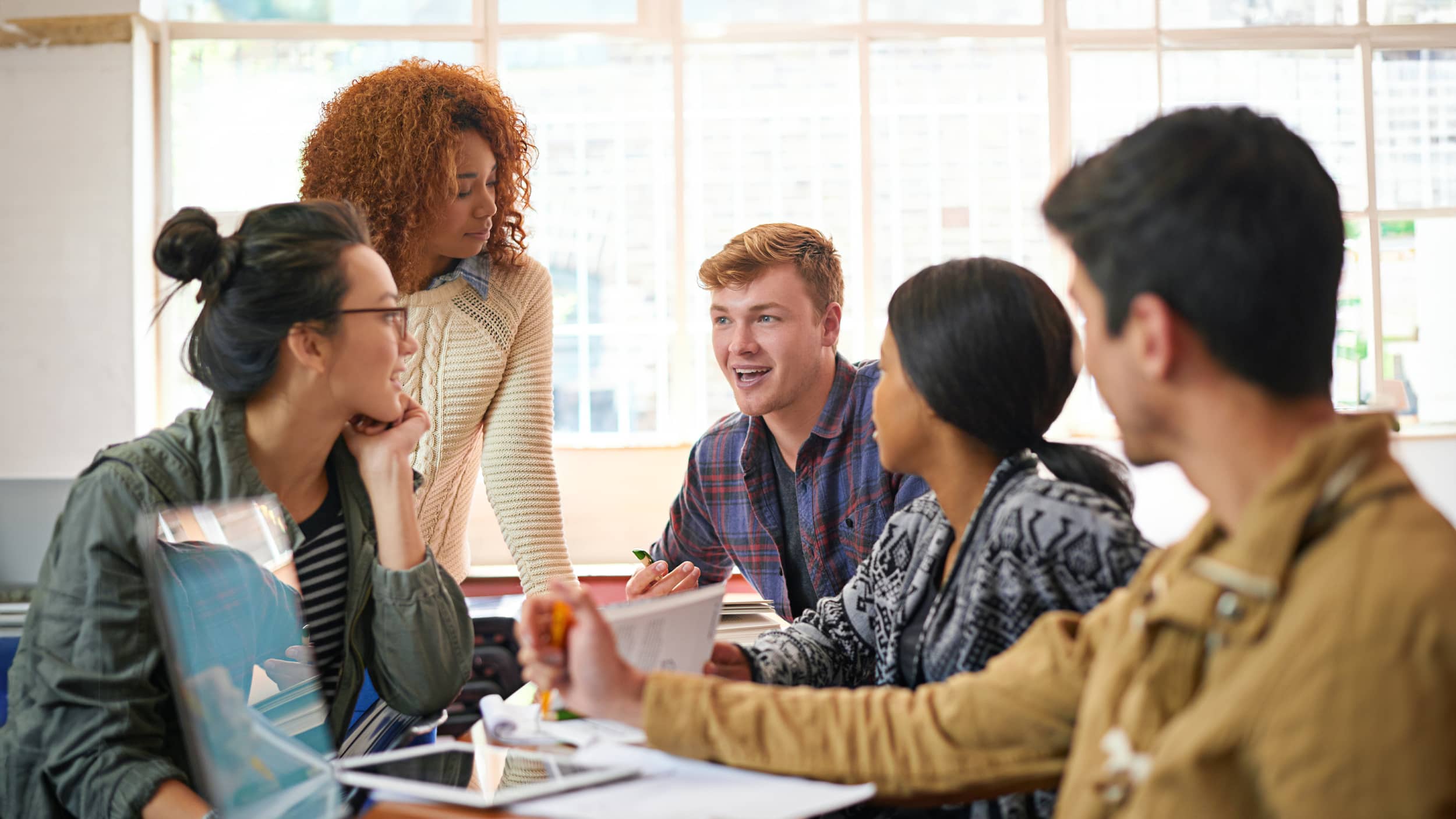 Students gathered around a table collaborating on an information technology project.