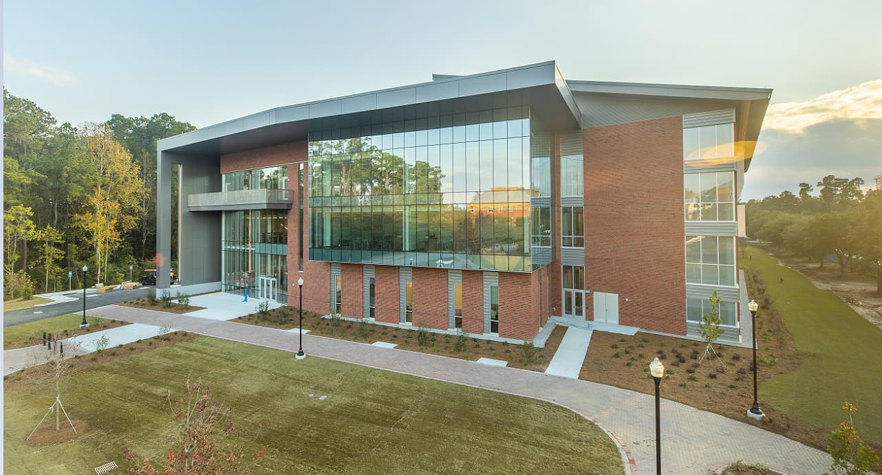 Exterior view of the ERB building with modern glass architecture surrounded by trees and landscaped walkways.