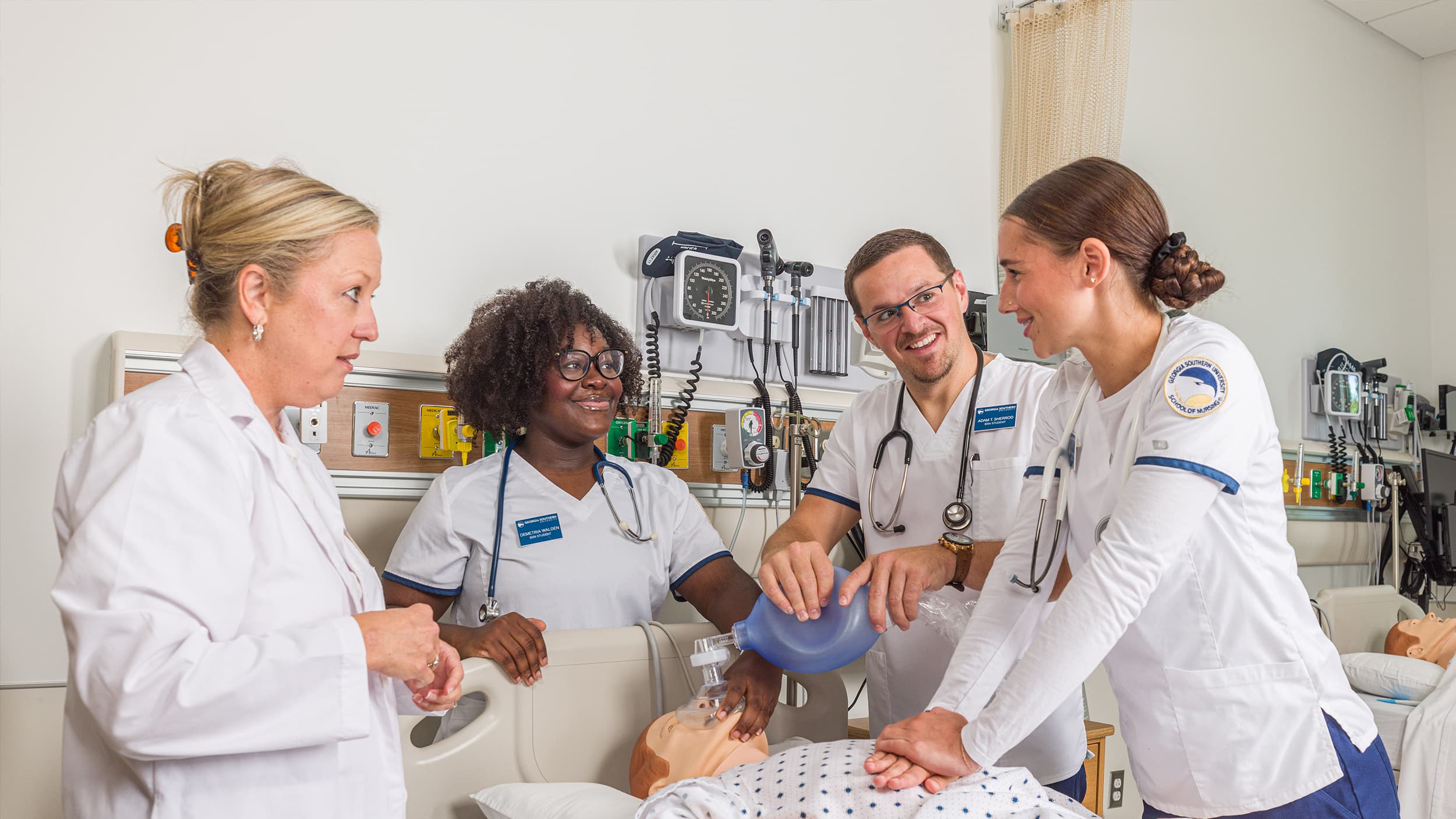 Three nursing students in a lab receiving instruction and practice on CPR and first aid cerfitications.