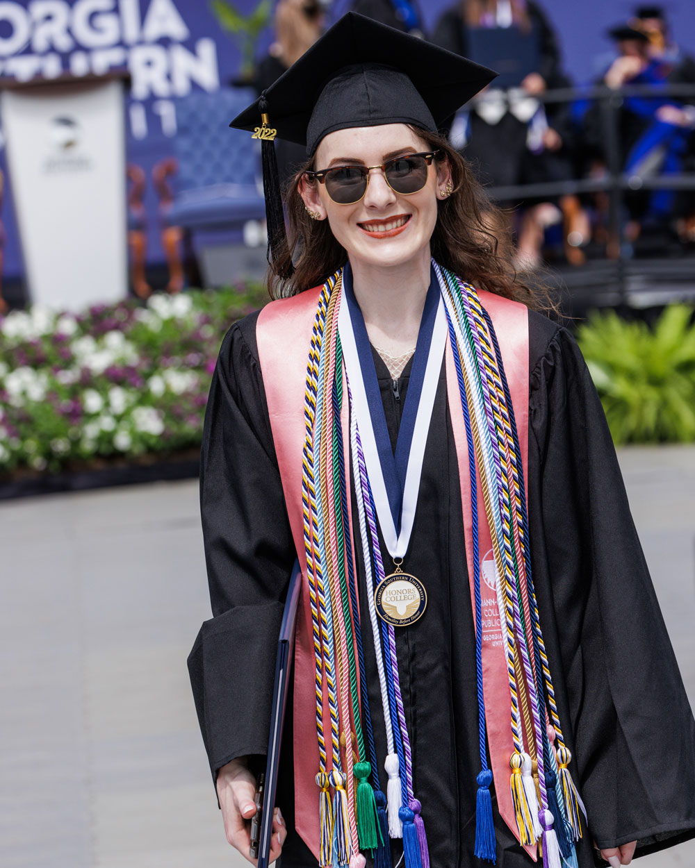Georgia Southern graudate Gabi Wiggill standing in graduation gown with tassels and stole.
