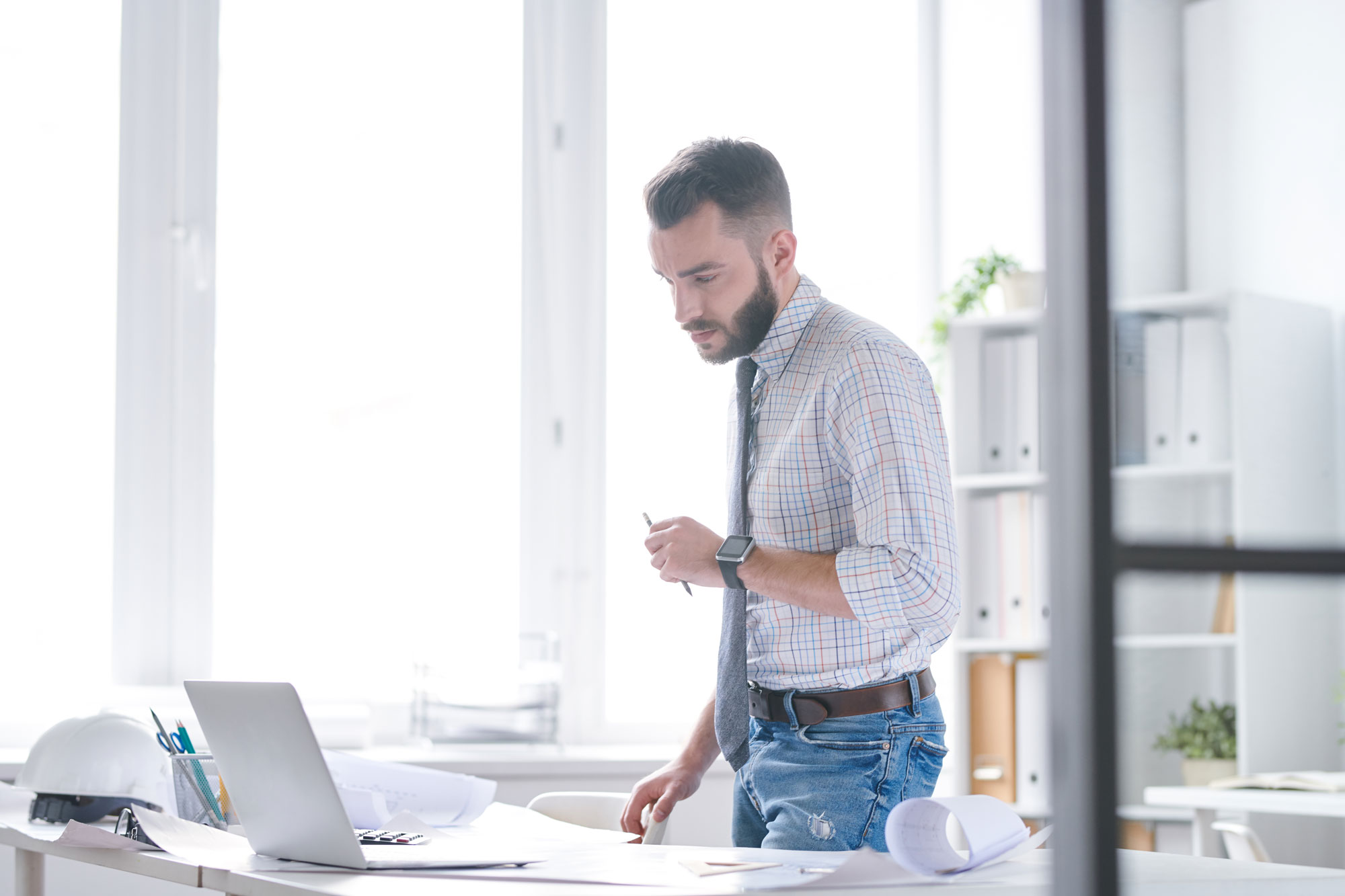An adult man works from a well lit office while working a construction job to complete his adult education online.