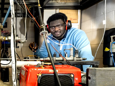 A B.S. in Construction Management student from Georgia Southern wears hearing protection while standing near pipes and various tubes during a co-op experience.