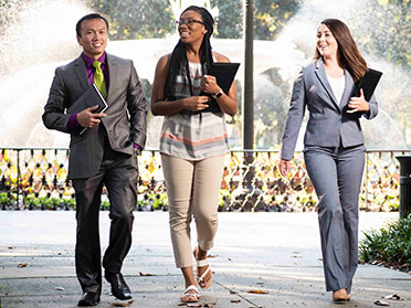Dressed in suits or business casual clothing, three students from Georgia Southern's Department of Economics hold folders while walking toward a mock interview.