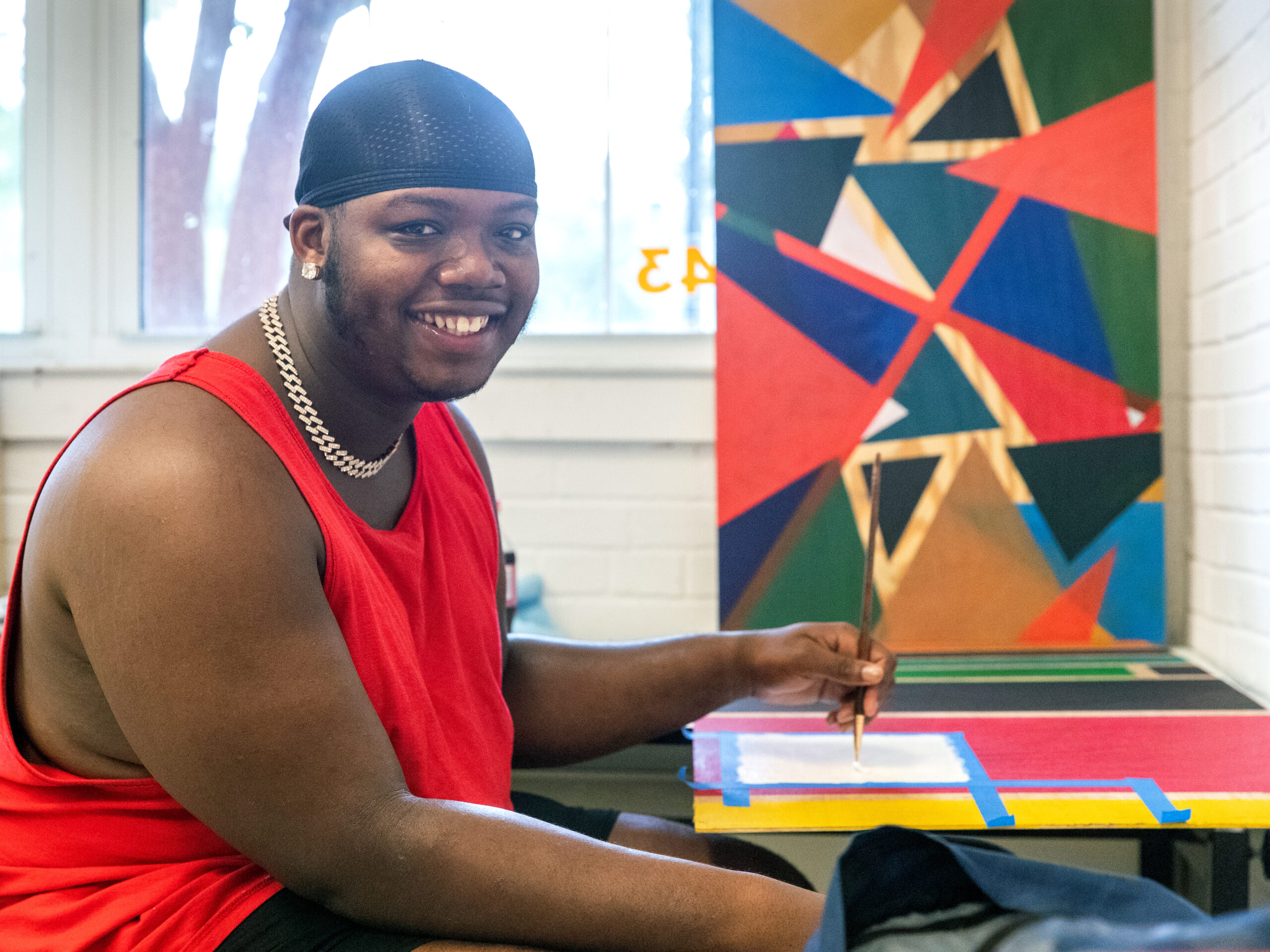 Georgia Southern art student in studio classroom, painting abstract geometric piece with acrylic media.