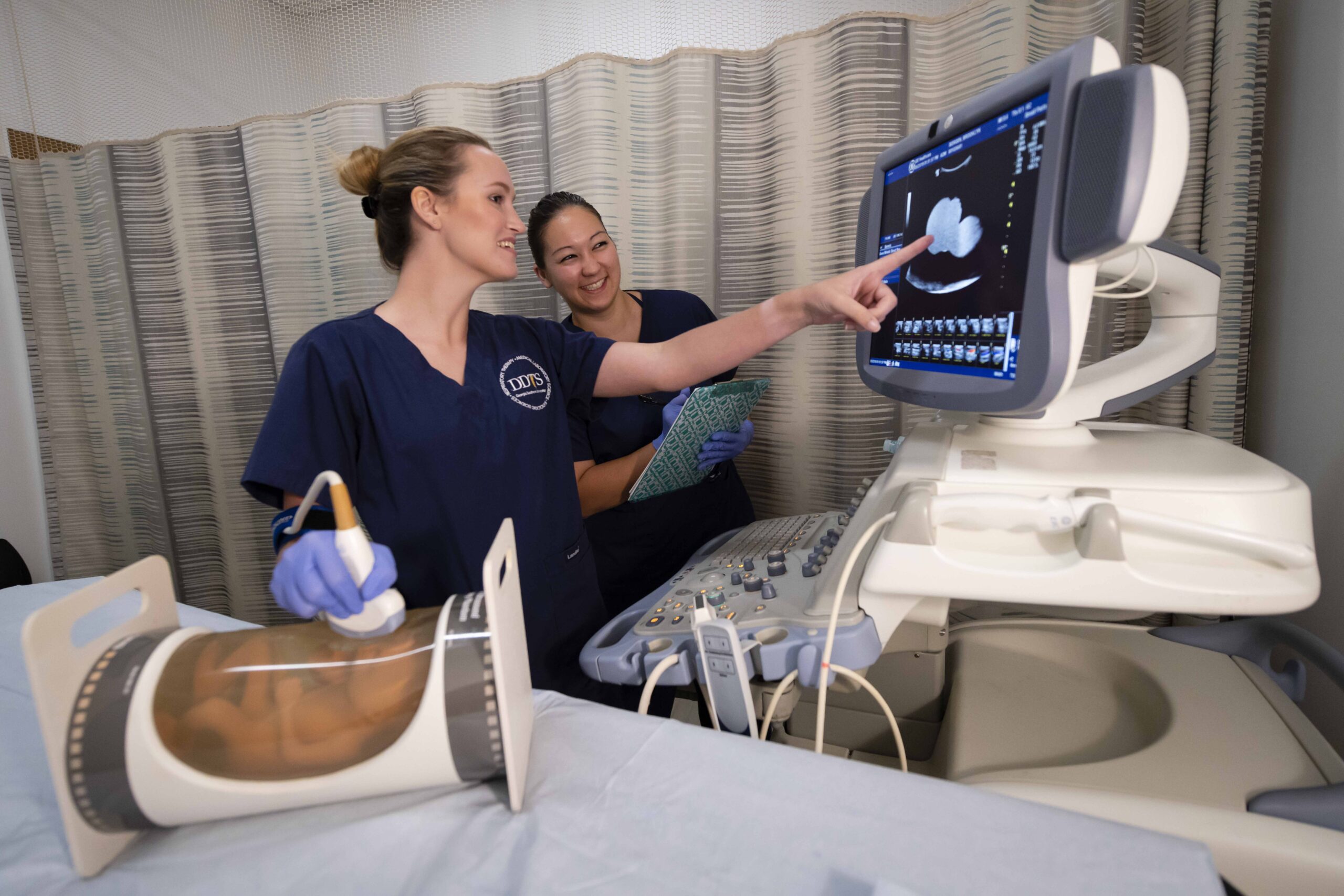 Georgia Southern student learning how to use sonogram equipment by watching a professional.
