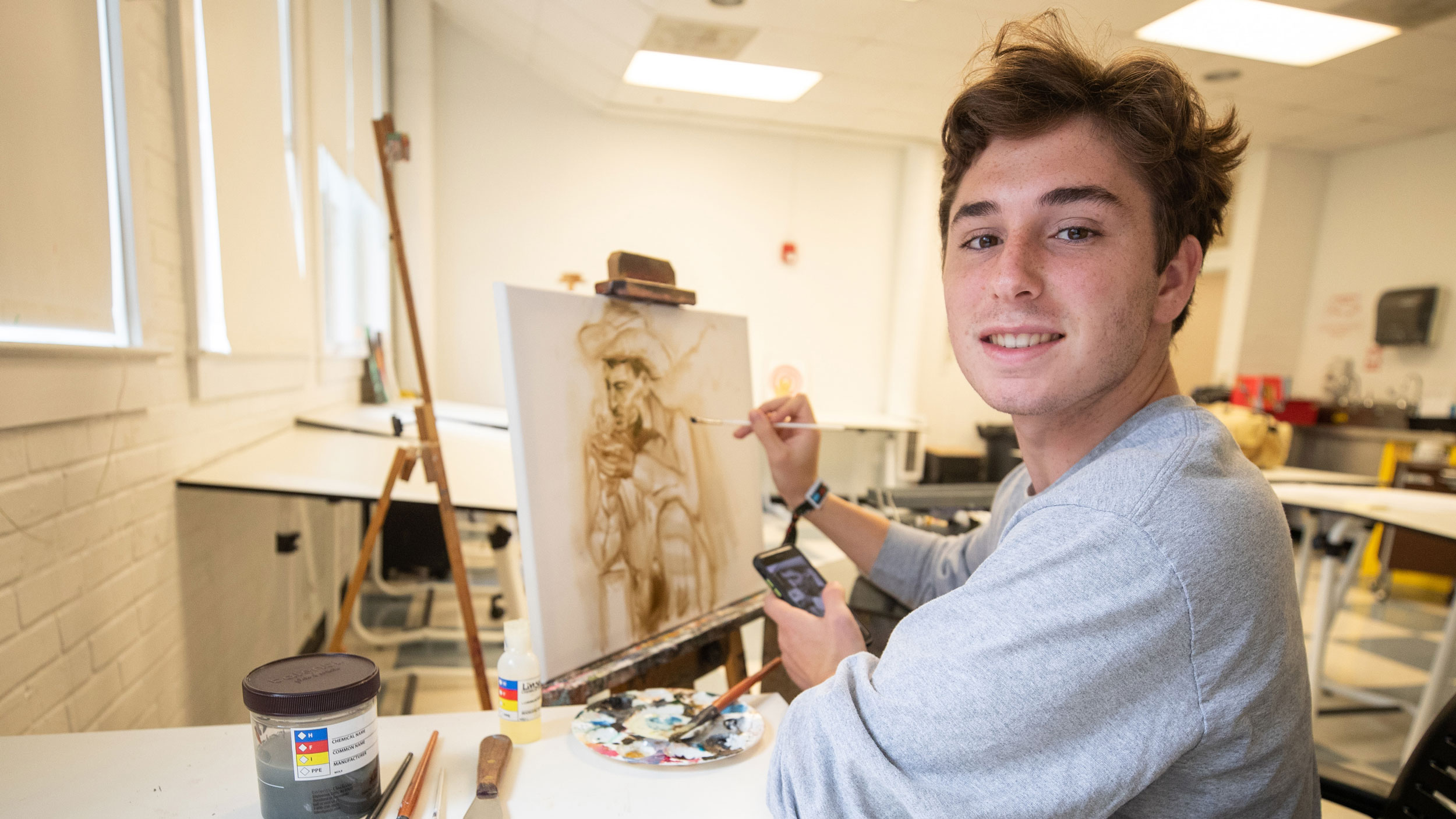Painting at an easel, Georgia Southern Student working on an art feature.