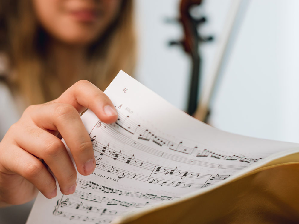 A Georgia Southern violinist studies sheet music for an upcoming music concert in a performance hall.