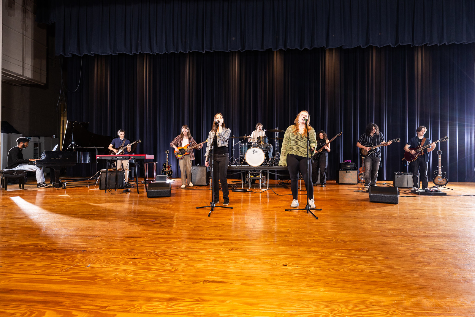 Students perform on stage as members of a musical ensemble.