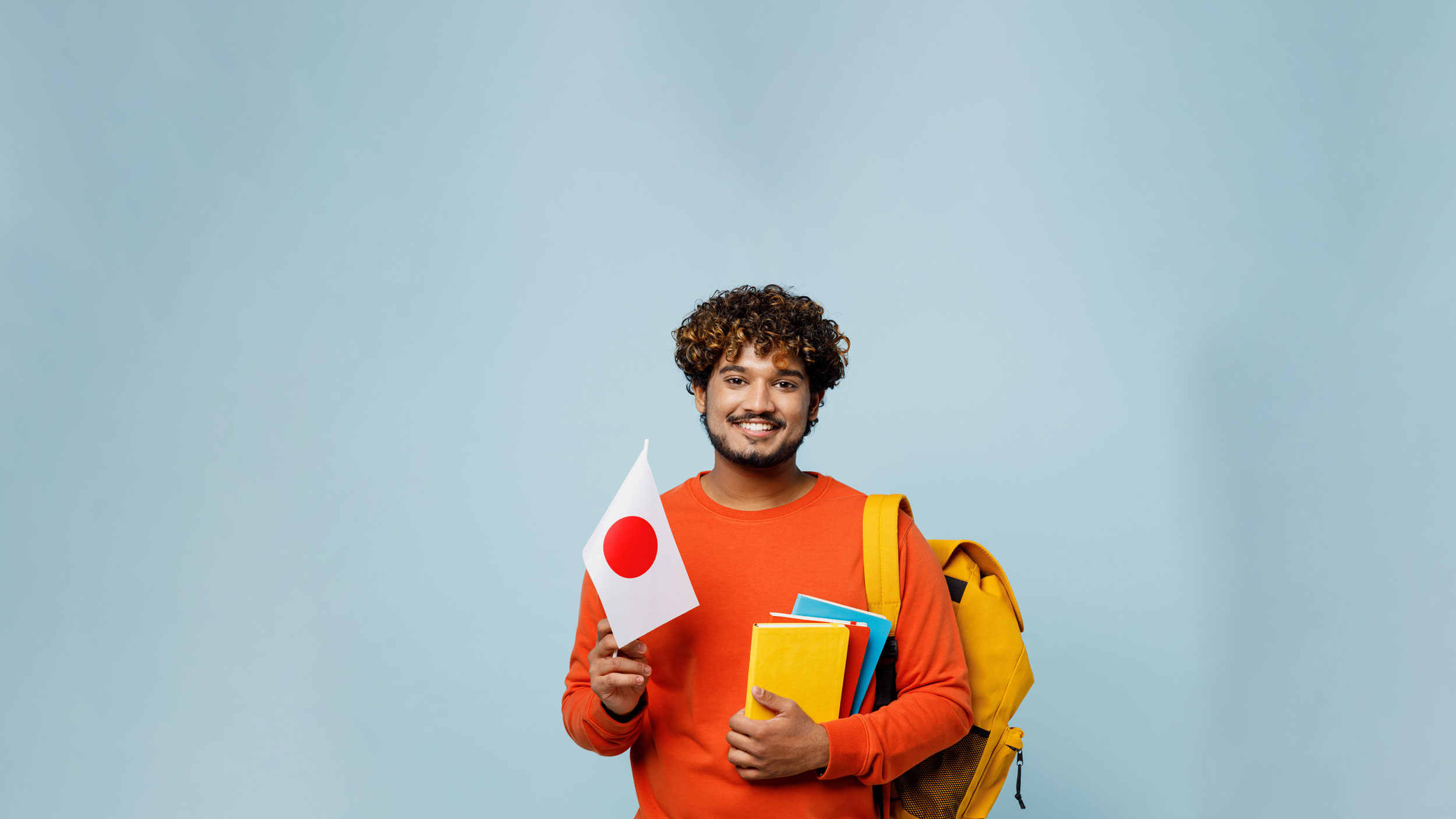 Georgia Southern student holding notebooks in one hand and a Japanese flag in the other.