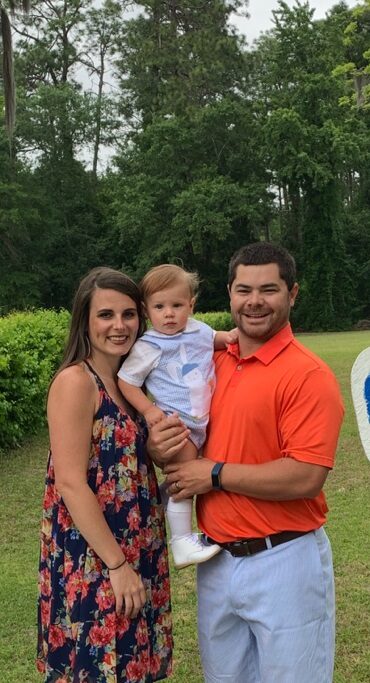 Benjamin Mitchell stands outdoors with his family