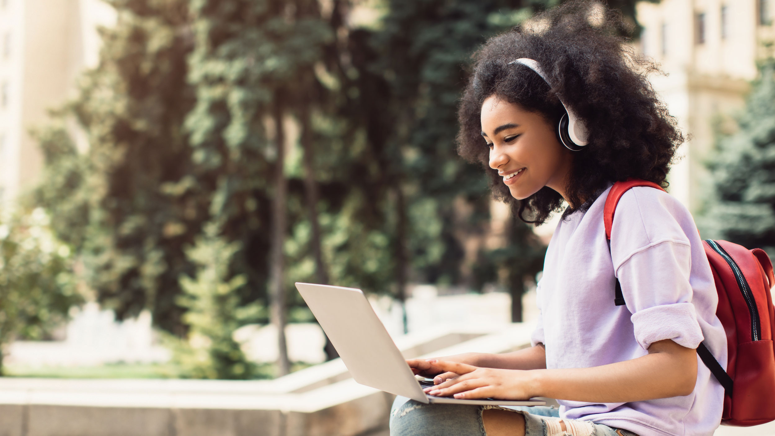 Georgia Southern student sitting on campus with headphones on and her laptop out.