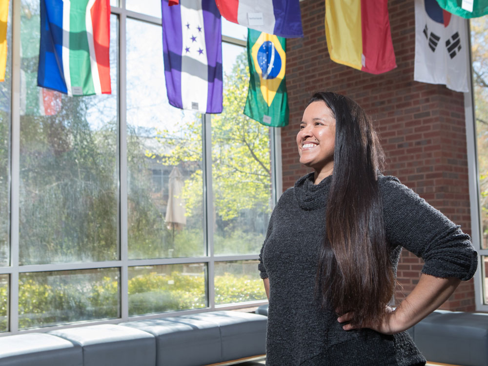 A Georgia Southern student smiles in front of international flags.