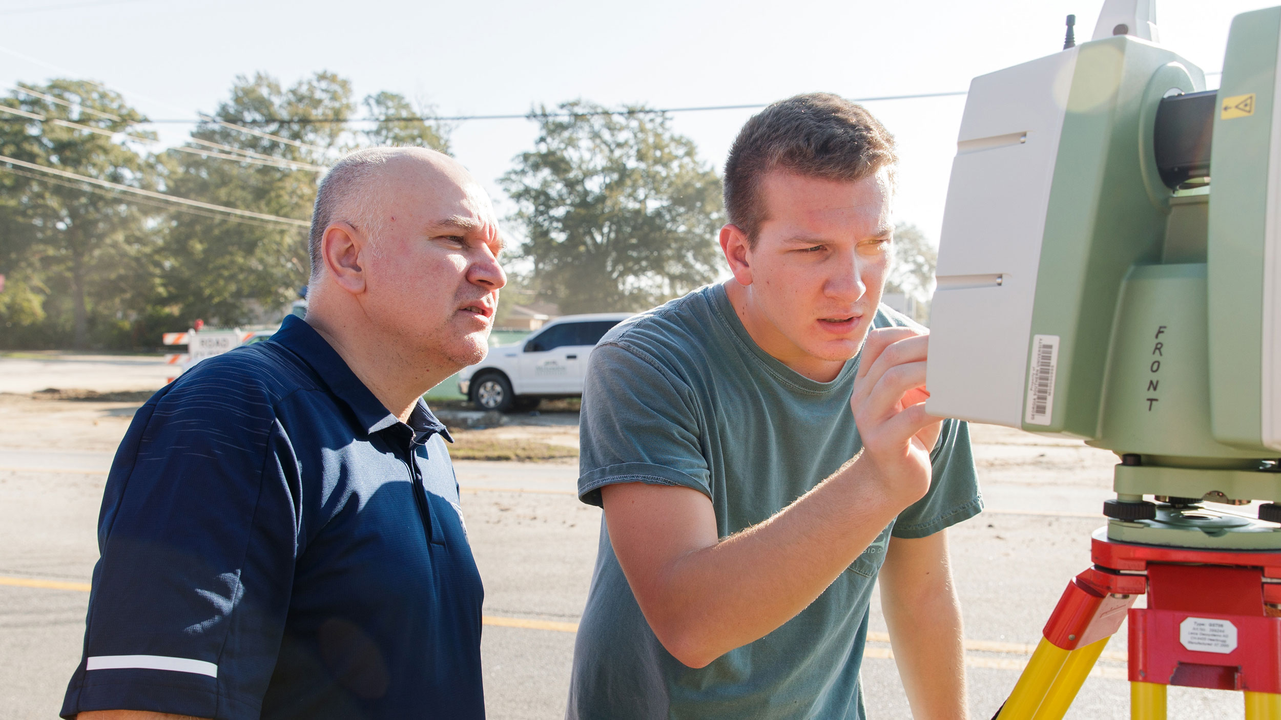 A student and professor from Georgia Southern's M.S. in Civil Engineering program use surveying equipment outdoors