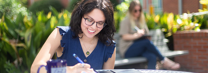 A Georgia Southern student takes notes outside the beautiful campus with coffee.