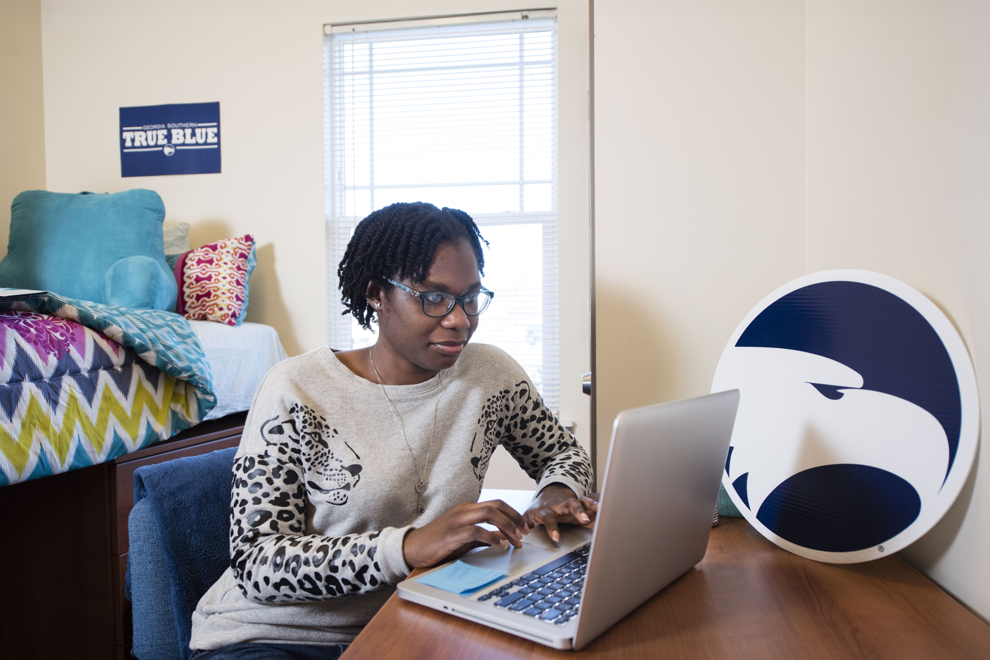 A Georgia Southern adult student works from a desk in her dorm.