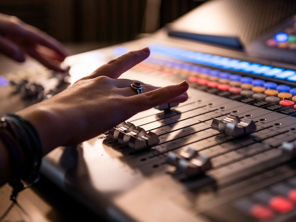 Georgia Southern student's hands adjust knobs on a production board for musical post production in music technology.