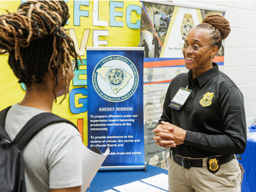 A Georgia Southern students speaks with a badged officer in the MS in Criminal Justice program.