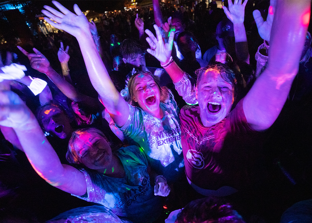 Students at a party with glow in the dark dust on them.