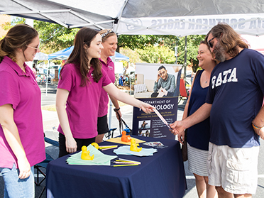 A Group of Georgia Southern students converse around the psychology table at a student organization event.