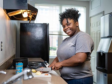 A student chops vegetables in a kitchen area inside one of Georgia Southern's residence halls