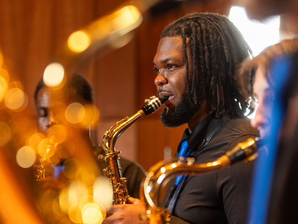A Georgia Southern saxophone player performs with other woodwinds in a concert performance hall.