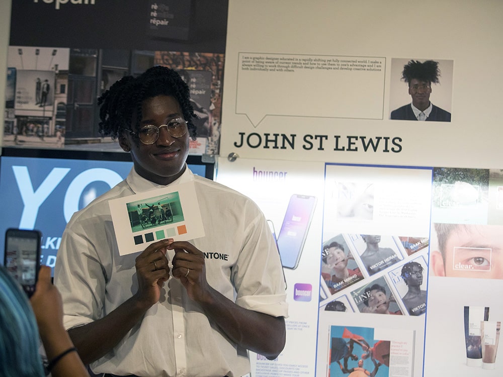 Holding a postcard-sized work, a Georgia Southern BFA in Studio Art student presents their portfolio in an exhibition space