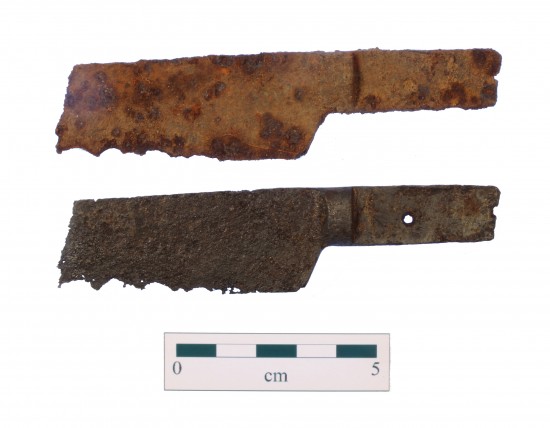 Approximately 10 centimeter long piece of rusted metal shaped like part of a knife with a broken blade, severely corroded edge and a tang with a hole for attaching a handle. It is shown before and after cleaning.