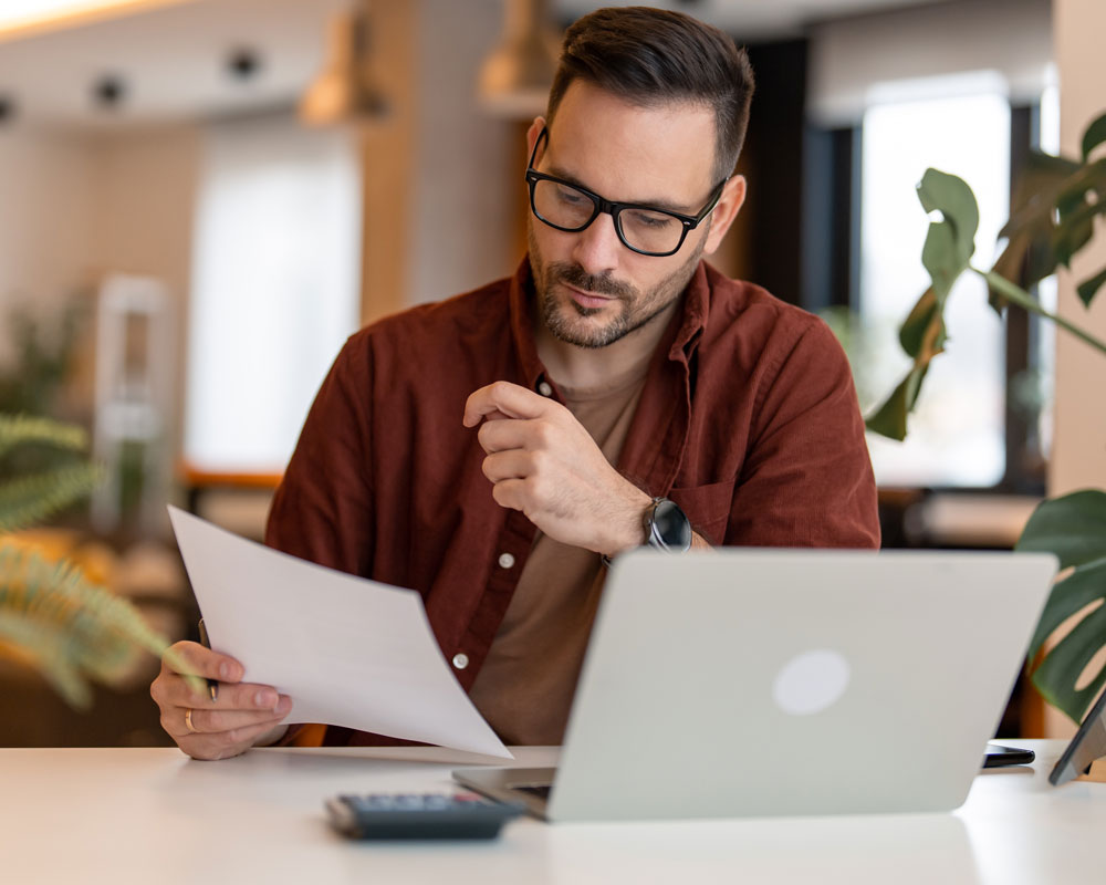 Adult male using laptop sitting at the table in home office.
