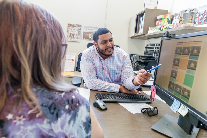 A man pointing to something on a computer screen with a pen while a woman looks on
