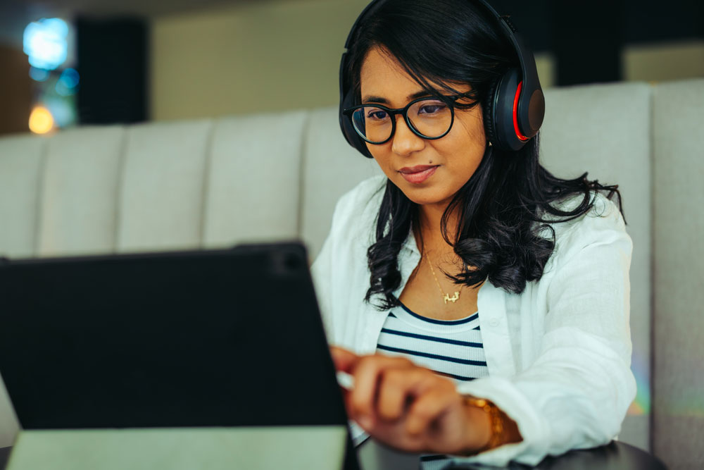 GS Online student sitting with a tablet and headphones.