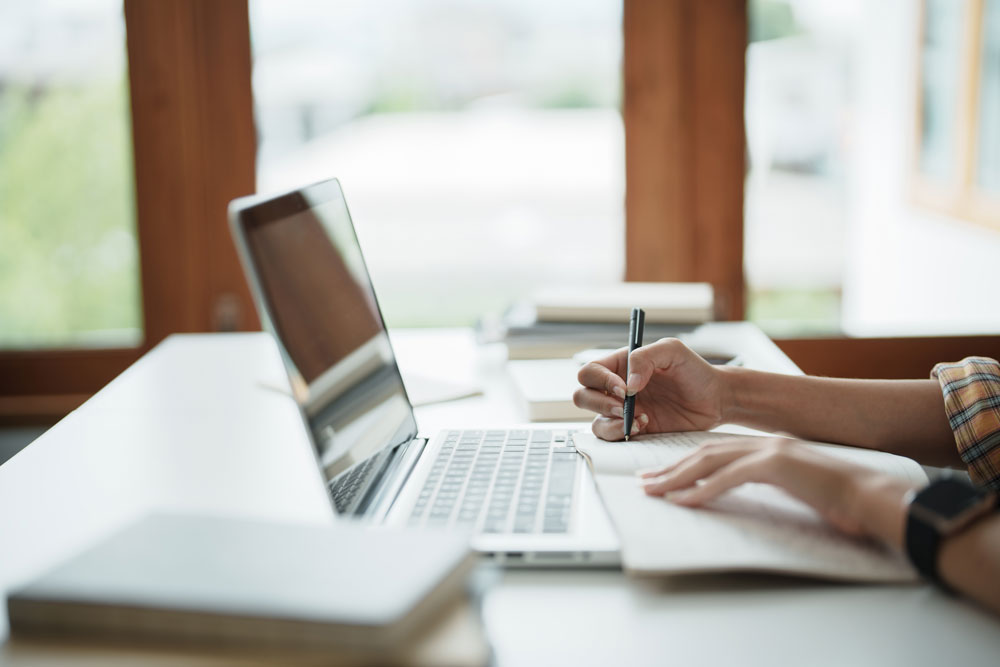 Young woman at a desk with a laptop and books.
