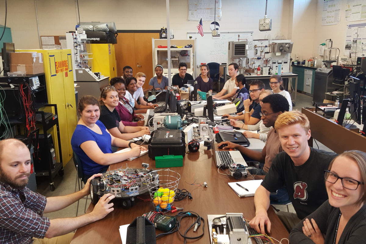 ENERGY participants posing for a picture with various technologies on the table