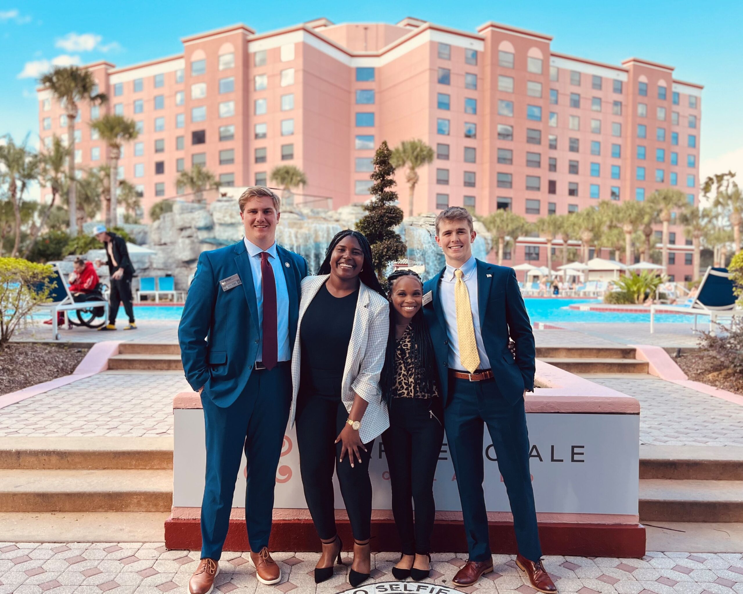 group of students posing for a picture in front of a hotel